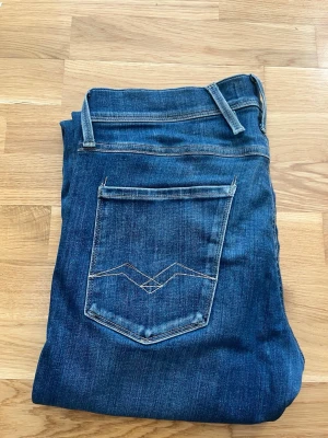 Blå slim fit jeans med broderad ficka - Snygga blå slim fit jeans med klassisk femficksdesign och coolt broderi på bakfickan. Jeansen har normal midja, smal passform och är gjorda i stretchigt denim för extra komfort. Perfekta till vardagslooken och lätta att matcha med olika stilar. Skickas snabbt och hör av er vid minsta funderingar!!!