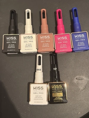 KISS New York Gel Pro nagellack set - Säljer ett set med KISS New York Gel Pro nagellack i flera färger: svart, vit, nude, rosa, blå samt base coat och top coat. Flaskorna har fyrkantig form och penselhandtag i matchande färg. Perfekt för dig som gillar att variera dina naglar med olika nyanser och finish.