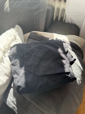 Svarta täckbyxor från North Bend - Säljer ett par svarta täckbyxor från North Bend med stora fickor och dragkedja. Perfekta för kalla dagar och outdoor-aktiviteter. Byxorna har knappstängning i midjan och är tillverkade i slitstarkt material.