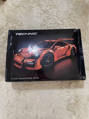 Lego Technic Porsche 911 GT3 RS - Säljer ett Lego Technic set, Porsche 911 GT3 RS, modellnummer 42056. Byggsatsen är orange och svart och innehåller 2704 delar. Perfekt för dig som gillar bilar och utmanande byggprojekt. Lådan har en snygg design med bilen i fokus.