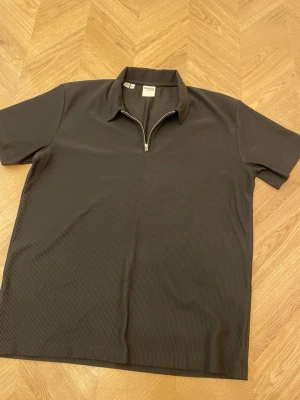 Svart ribbad skjorta Selected Homme - Kortärmad svart ribbad skjorta från Selected Homme med krage och half zip-dragkedja framtill. Skjortan har en stilren look och är tillverkad i ett mjukt material som känns bekvämt mot huden. Perfekt för dig som gillar en modern och avslappnad stil.