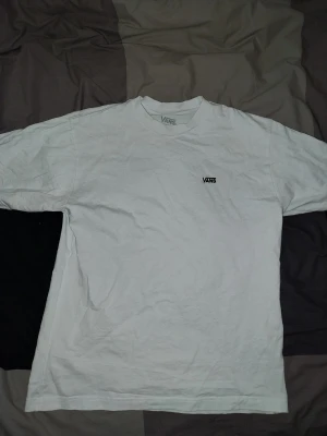 Vit Vans T shirt - Vit t-shirt från Vans i loose fit-modell. Klassisk rund halsringning och diskret Vans-logga broderad på bröstet. Tillverkad i mjuk bomull som känns skön mot huden. Perfekt för en avslappnad och enkel stil.