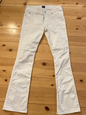 Vita bootcut jeans från Lee - Snygga vita low waist bootcut jeans från Lee med klassisk femficksmodell och utsvängda ben. Jeansen har dubbla knappar i midjan. Perfekta för en trendig och avslappnad stil, köpte nya för 1000kr och använda 2 gånger💓säljer pga att de inte kommer till användning💓
