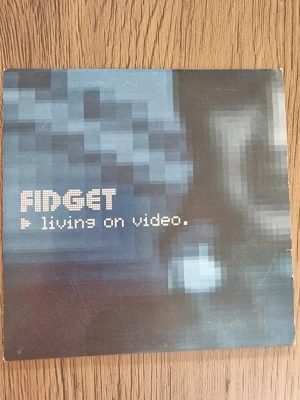 Fidget - Living on Video CD-singel - CD-singel med Fidget, titeln 'Living on Video'. Omslaget har en blå och svart pixlad design med vit text. Innehåller två låtar: 'Living on Video' och 'The Law of Least Resistance'. Släppt av Silence Records år 2000.