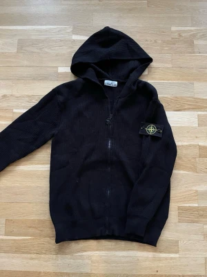 Svart hoodie från Stone Island - En superunik tröja! Knappt anvand, i nyskick. Tröjan ar tjock, varm och perfekt för våren, både för en fin och bekväm look. Tröjan ar för män. Den är i storlek M. Passar dig som ar ungefar 170-185 cm lång och väger 60-80kg. Hör gärna av dig om du har några frågor eller funderingar!