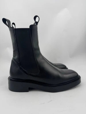 Gant Chelseaboots - Svarta chelsea boots Fallwi i skinn från Gant. Gedigna boots med fin silhuett. Högre skaft. Innerfoder i textil och innersula i skinn. Yttersula i gummi med bra mönster för bästa grepp på underlaget. Ett par tidlösa boots som blir snyggare med åren! Sparsamt använda, väldigt fint skick! Nypris 2499kr