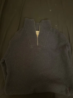 Mörkblå stickad halvzip från Zara - Säljer en mörkblå stickad tröja från Zara med halvzip och hög krage. Tröjan har grov ribbstickning och är perfekt för kyliga dagar. Enkel och stilren design som passar till det mesta.
