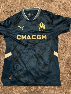 Marseille matchtröja blå Puma - Storlek M. Snygg blå fotbolls tröja från Marseille som är perfekt för sommaren.