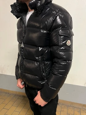Moncler Maya - Storlek S - Svart glansig vinterjacka från Moncler. Jackan är i storlek S och nyskick, inga tecken på använd. Väldigt bekväm och varm samt väldigt snygg, rekommenderar starkt. Hör av dig vid intresse/funderingar. PRIS KAN DISKUTERAS!