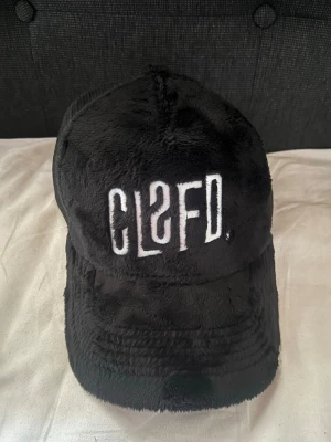 Classified keps - Säljer en svart keps från classified med mjuk plysch framtill och mesh baktill för extra ventilation. Kepsen har broderad vit logga framtill och justerbar snapback. Perfekt för dig som vill ha en unik och trendig accessoar.