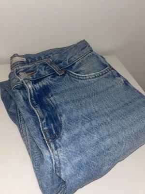 Ljusblå raka jeans med vintage-look - Säljer ett par ljusblå jeans med klassisk femficksmodell och raka ben. Jeansen har en snygg tvättad vintage-look och silverfärgad knapp. Perfekta för en avslappnad stil och passar till det mesta i garderoben.