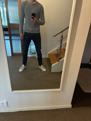 Ljusgrå kabelstickad tröja ”gant” - Säljer en ljusgrå kabelstickad tröja med rund hals och ribbade muddar. Tröjan är i gott skick och av märket Gant. Modellen på bilden är 184 och väger  67kg