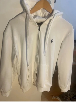 Vit hoodie med dragkedja från Polo Ralph Lauren - En väldigt fin och Ralph lauren zip hoodie i ny skick. Väldigt efter traktad och perfekt till våren. Storlek är M men passar mer s skulle jag säga.