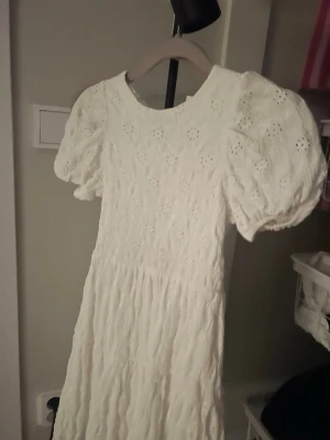 Vit spets-blommog klänning - Säljer en jätte söt kort vit klänning från Zara som är slutsåld,har används en gång på midsommar för 2 år sedan men har inte kommit till användning. Storleken är runt 150 
