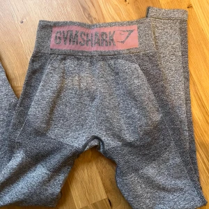 Grå leggings från Gymshark - Snygga grå leggings från Gymshark med hög midja och elastisk passform. Perfekta för träning med sitt bekväma och flexibla material. Gymshark-logga i midjan..