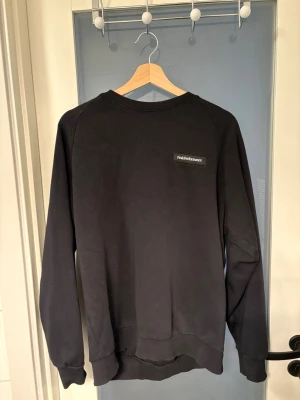 Svart sweatshirt från Peak Performance - En stilren svart sweatshirt från Peak Performance med diskret logga på bröstet. Tröjan har rund halsringning, långa ärmar och ribbade muddar vid ärmslut och nederkant. Perfekt för en avslappnad och sportig look.