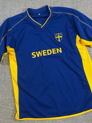 Vintage Sweden Football Jersey Siemens Sponsor Tre Kronor Blue Yellow Colorway XL - Vintage Sweden football jersey in iconic blue/yellow colorway. Tre Kronor crest, SWEDEN spellout front and SIEMENS back hit for that early 2000s national team look. Relaxed fit with raglan sleeves. Measurements: P2P 57cm, length 74cm, waist 55cm. Good vintage condition with normal wear. Compare with your own jersey for best fit.