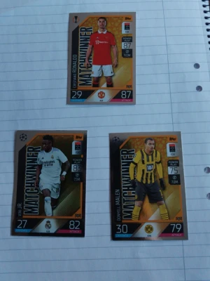 Match Attax fotbollskort Matchwinner - Säljer tre Match Attax "Matchwinner Exklusiva" fotbollskort från Topps Ronaldo, Vini Jr. Och. Kortens design är färgstark med guldiga detaljer och statistik på framsidan. Perfekt för samlare eller dig som gillar fotboll och trading cards.