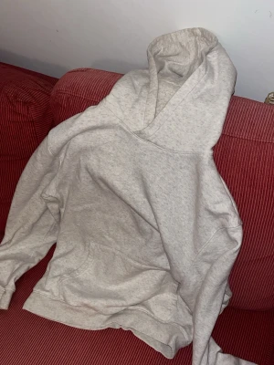 Ljusgrå hoodie med huva från Hm - En enkel och stilren ljusgrå hoodie med stor huva och magficka. Hoodien har ribbade muddar vid ärmslut och nederkant. Perfekt för en avslappnad och bekväm stil. Materialet känns mjukt och skönt mot huden.