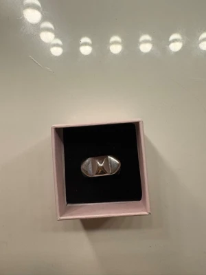 Silverfärgad chunky ring - Säljer en chunky ring i silverfärg med en upphöjd stjärndetalj på ovansidan. Ringen har en bred och robust form som ger ett coolt statement-intryck. Perfekt för dig som gillar unika accessoarer med lite edge.