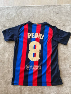 Barcelona tröja  - Snygg FC Barcelona fotbollströja med Pedri #8 på ryggen. Den är i bra skick och köpt i Barca. Bara att skriva vid funderingar mvh Liam😁