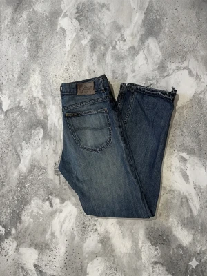 Lee Jeans  - Jeans från märket Lee Storlek: 31/32 (smal vi midjan) Färg: Blå Passform: Straight fit OBS! Finns ett par små hål på benen men inget man märker och slitning på vänster ben