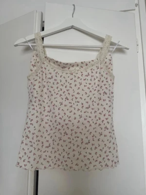 Blommig spetsdetaljerad pyjamas  - Söt linnetopp i ljusbeige med små rosa blommor och spetsdetaljer vid axelband och ringning. Toppen är ärmlös och har en mjuk, feminin look som passar perfekt till sommaren. Super fin pyjamas 💖