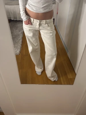 Vida vita jeans med låg midja - Säljer ett par snygga vita jeans med låg midja och raka, vida ben. Jeansen har klassisk femficksdesign och stängs med knapp och dragkedja. Helt oanvända och är i storlek 36. Jag är 172 och de är långa för mig🥰🥰