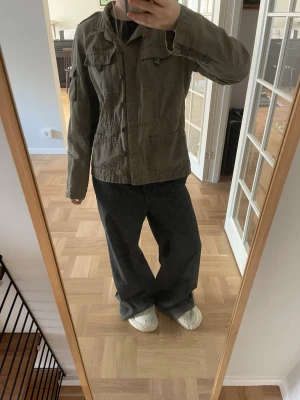 Khaki jeansjacka  - Snygg khaki färgad jeansjacka med flera praktiska fickor framtill och på armen. Materialet känns slitstarkt och jackan har en bra passform. Är i storlek 40 men passar mer en 36/38, s/m. Ställ frågor!!