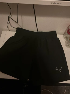 Svarta shorts från Puma - Säljer ett par svarta shorts från Puma med elastisk midja och diskret Puma-logga på benet. Perfekta för träning eller chill. Tillverkade i lätt och bekvämt syntetmaterial som andas. Bad shorts 