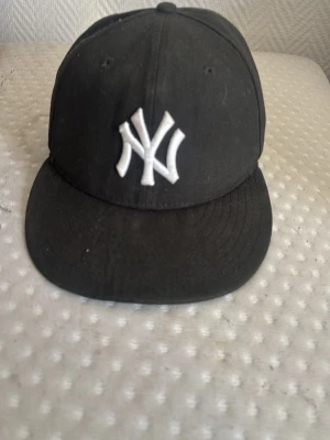 Svart New Era Yankees keps - Säljer en svart New Era keps med klassiskt New York Yankees broderat vitt logotyp framtill. Kepsen har rak skärm och broderad New Era-logga på sidan. Perfekt för dig som gillar streetwear och sportig stil. Kan gå ner i pris vid snabb affär 
