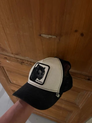 Svartvit truckerkeps med pantermärke - Svartvit Panther keps i bra skick 