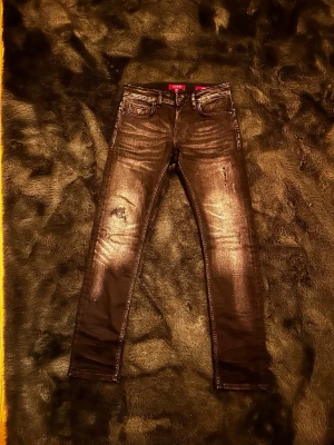  Guess jeans - Säljer ett par svarta skinny jeans från Guess med slitna detaljer och snygg tvätt. Jeansen har fem fickor, låg midja och smal passform. Perfekta för dig som gillar en trendig och avslappnad stil.