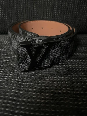 L-v svart rutigt bälte - Säljer ett helt nytt riktigt snyggt svart L-v bälte med svart logga.