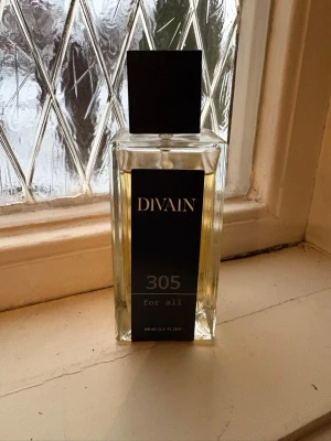 DIVAIN 305 for all parfym - Tom Ford oud wood. Använt 1/10 av flaskan så ca 90ml kvar. Doft för både kvinnor och män. DIVAIN 305 for all är en unisex parfym i en stilren, rektangulär glasflaska med svart etikett och svart fyrkantigt lock. Flaskan rymmer 100 ml och har en modern, minimalistisk design som passar alla.