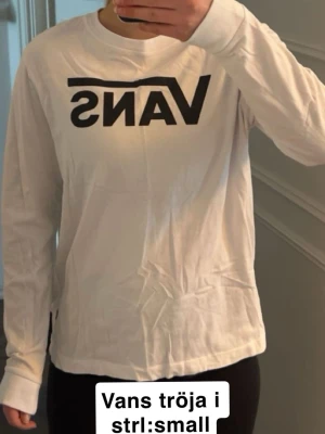 Vit långärmad Vans långärmad tshirt  - Säljer en vit långärmad t-shirt från Vans med stor svart logga framtill. Tröjan har rund halsringning och är gjord i mjuk bomull. Den är knappt använd men tyvärr skrynklig då den inte används av mig.