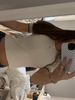 Vit ribbad croppad topp - Snygg vit croppad topp med ribbad struktur och korta ärmar. Perfekt till jeans eller kjol för en clean och enkel look. Figurnära passform och rund halsringning.