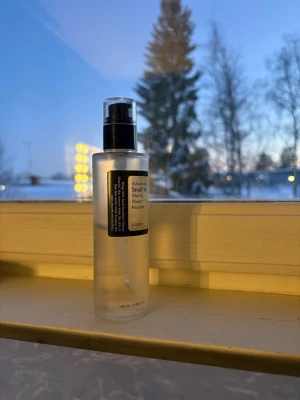 COSRX Advanced Snail 96 Mucin Power Essence - En genomskinlig toner i pumpflaska från COSRX, Advanced Snail 96 Mucin Power Essence. Flaskan är cylinderformad och gjord av plast med svart pump och etikett. Innehållet är klart och lättflytande, perfekt för återfuktning och glow.