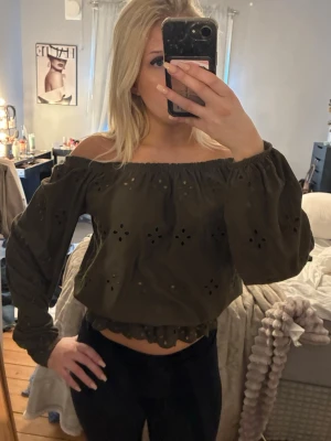 Olivgrön offshoulder blus med broderi - olivgrön blus med offshoulder-modell och långa ärmar. Blusen har broderade detaljer och en croppad passform 