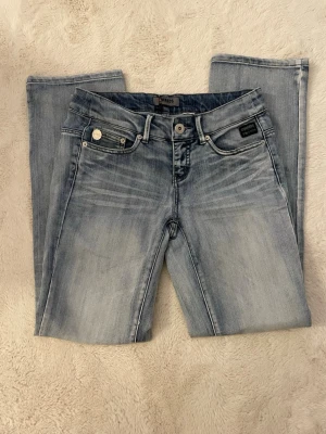 Ljusblå bootcut jeans från Only - Snygga ljusblå jeans från Only med bootcut passform och klassisk femficksdesign. Jeansen har slitningar och tvättade detaljer framtill för en trendig look. Tillverkade i mjukt denimtyg som ger en bekväm känsla hela dagen. Jeansen har en liten kaffefläck på vänster lår, syns inte från långt håll.