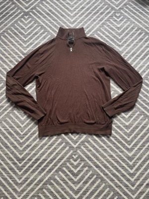 Brun stickad tröja med halv dragkedja - Snygg brun stickad tröja från Jack & Jones med halv dragkedja i halsen. Tröjan har lång ärm, ribbade muddar och en stilren look som passar perfekt till jeans eller chinos. Materialet känns mjukt och bekvämt mot huden.