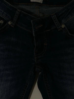 Mörkblå jeans från 157 Blaze - Snygga mörkblå jeans från 157 Blaze med klassisk femficksdesign och kontrastsömmar. Jeansen har ganska låg midja och är bootcut, perfekta till vardagslooken. Materialet är slitstarkt denim i bomull med en cool tvättad finish. 