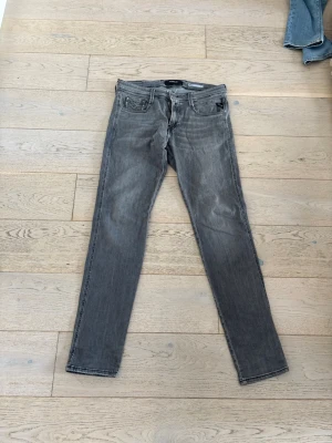 Gråa slim fit jeans från Nudie - Säljer ett par gråa slim fit jeans från Nudie Jeans med klassisk femficksmodell och svarta sömmar. Jeansen har normal midja och raka ben, tillverkade i mjuk bomullsdenim. Perfekta för en avslappnad och stilren look.
