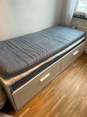 Brimnes säng/dagbädd - Brimnes säng/dagbädd som även går att göra till dubbelsäng med 2 stycken tillhörande förvaringslådor och 2 st blåa madrasser till. (Vita ingår inte)  Måtten finns på andra bilden.   Finns några få skavanker men fortfarande i väldigt gott skick samt går att få den nermonterad om man vill.  Djur finns i hemmet.  Billigare vid snabb affär och HÄMTAS i Södertälje.