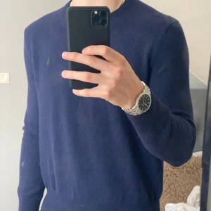 Mörkblå tröja från Polo Ralph Lauren - Säljer en stilren mörkblå tröja från Polo Ralph Lauren med broderad grön logotyp på bröstet. Tröjan har en klassisk design med rund hals och långa ärmar. Perfekt för kyligare dagar men passar nästan alla tillfällen😊