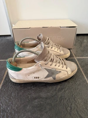 Golden Goose - Hej, jag säljer nu dessa otroligt snygga Golden Goose skor. | Väldigt snygg färg som passar till allt, skorna är ganska slitna vilket visas på bilderna men har mycket kvar att ge. | Storlek 40 men passar mer 41. | Endast skorna ingår, hör av er vid frågor!🌟