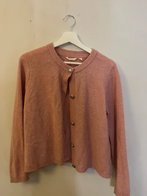 Rosa kofta med rund hals - Mysig rosa kofta med silverfärgade knappar framtill.