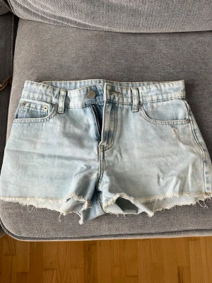 Ljusblå jeansshorts med rå kant - Säljer ett par ljusblå jeansshorts med fransig kant.  Perfekta för varma dagar och ger en avslappnad vibe. Dem är helt nya använda en gång, säljer för att de inte kommer till användning mer
