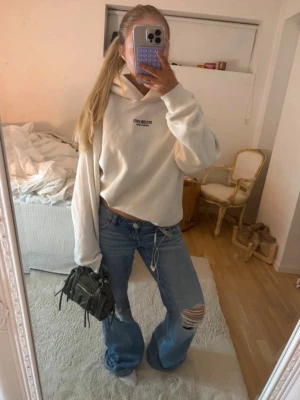 Vit hoodie från AMISU - Snygg vit hoodie  med svart logga på bröstet. Hoodien har en klassisk huva och en avslappnad passform, perfekt för en chill och trendig look. Tillverkad i mjukt material som känns skönt mot huden. Passar Overzised xs-m