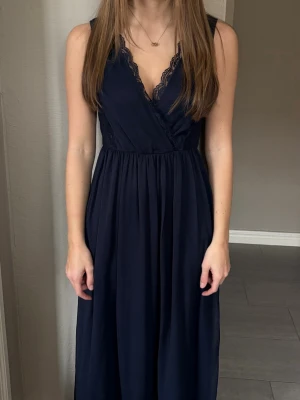 VILA Navy Blue Maxi Dress / Evening Gown - Elegant navy blue maxi dress from VILA, perfect for formal occasions such as prom, weddings, balls, or evening events. The dress features a flattering wrap-style bodice with delicate lace details and a flowing, lightweight skirt that falls beautifully.  ✨ Only worn once ✨ Excellent condition – like new ✨ Feminine, timeless, and comfortable to wear  Size: XS / EU 34 Color: Navy blue Brand: VILA Length: Maxi / floor-length Fit reference: I am approximately 165 cm tall, and the dress reaches the fl